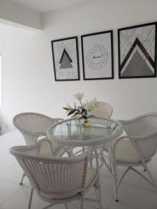 a dining room with a glass table and wicker chairs at Village Duplex, Vilas do Atlântico in Lauro de Freitas