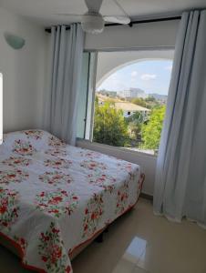 a bedroom with a bed and a large window at Village Duplex, Vilas do Atlântico in Lauro de Freitas