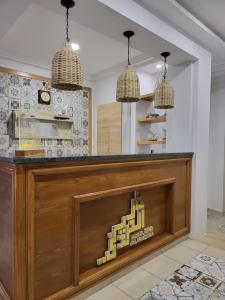 a kitchen with a large wooden counter with two pendant lights at Hotel Dar Al Madina in Mahdia