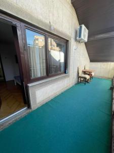 Guesthouse 12a في بريشتيني: غرفة بها أرضية خضراء ونوافذ وطاولة