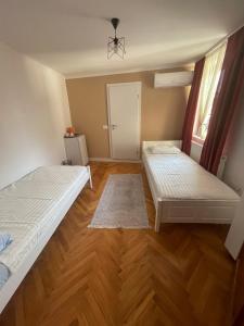 a bedroom with two beds and a wooden floor at Guesthouse 12a in Pristina