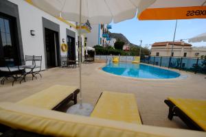 a swimming pool with benches and an umbrella at Enda Boutique Hotel Kalkan in Kalkan