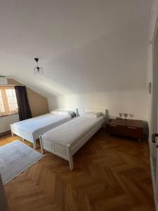 two beds in a room with wooden floors at Guesthouse 12a in Prishtinë