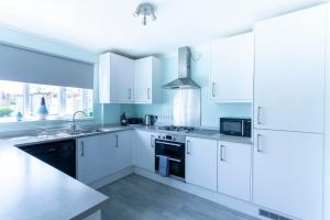 a kitchen with white cabinets and a stove top oven at Tankerton Town House, 1 parking space, 150m beach in Whitstable