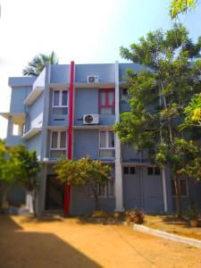 a large blue building with red windows and trees at Hotel Sunday - Townhouse Club Airport Trivandrum in Trivandrum