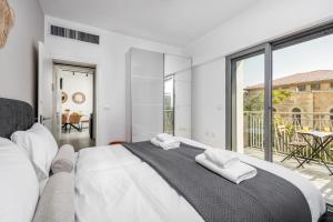 a white bedroom with a large bed and a balcony at 2BDR W parking shirat haneviim - Mamilla Area sea-u jerusalem in Jerusalem