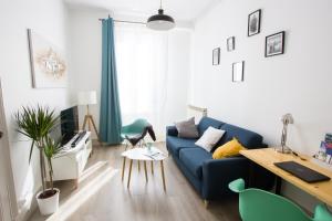 een woonkamer met een blauwe bank en een tafel bij Le 62 - Spacieux T2 avec JARDIN, parking & tramway in Grenoble