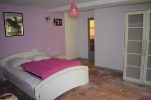 a bedroom with a white bed with a pink blanket at Le Moulin,19 bis rue de Beaudon, 45330 Augerville la riviere in Trézan
