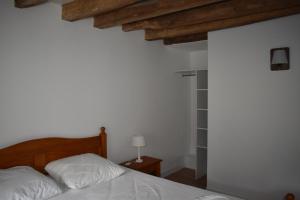 a bedroom with a bed with white sheets and wooden ceilings at Le Moulin,19 bis rue de Beaudon, 45330 Augerville la riviere in Trézan +3 photos