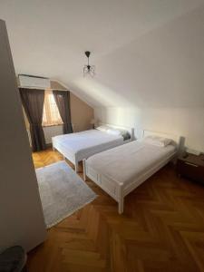 two beds in a room with wooden floors at Guesthouse 12a in Pristina