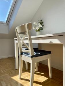 białe biurko z krzesłem i wazon kwiatów w obiekcie West46 Apartment mit Netflix & Prime w mieście Duisburg