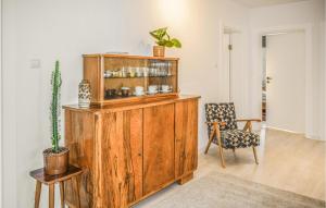 a wooden cabinet in a living room with a chair at Awesome Apartment In Darlowo With Kitchen in Darłowo