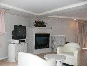 a living room with white furniture and a tv at Chateau Royale Inn in Lake Geneva
