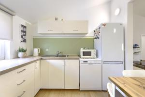 La cuisine est équipée de placards blancs et d'un réfrigérateur blanc. dans l'établissement Homestay Pula, à Pula
