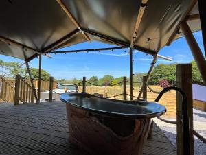 una vasca da bagno posta su un ponte con un baldacchino di Jungle Book Safari Tent a Tenby