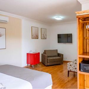 um quarto com uma cama, um sofá e uma televisão em Bliss Hotel Vale do Café em Vassouras