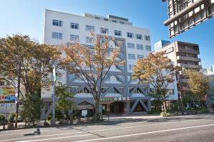 un edificio blanco con árboles frente a una calle en Onsen Hotel Nakahara Bessou Nonsmoking, Earthquake retrofit, en Kagoshima