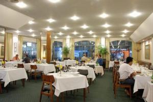 a restaurant with white tables and people sitting at them at Hotel Cervantes in Mendoza