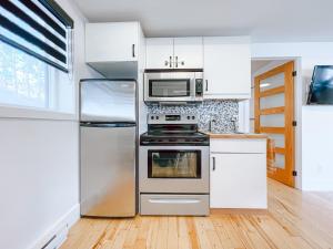 a kitchen with stainless steel appliances and white cabinets at Complexe LIVTremblant by Gestion ELITE - LIV6 in Mont-Tremblant