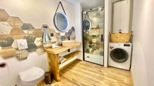 une salle de bain avec une machine à laver et un lave-linge dans l'établissement La Grange - Gîte de Prestige La Rochelle, à Saint-Médard-dʼAunis