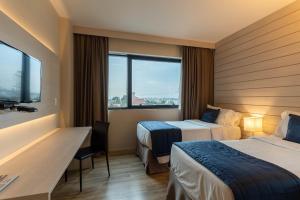 um quarto de hotel com duas camas e uma secretária em Hotel Contemporâneo - Royal Palm Hotels & Resorts em Campinas