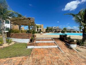 a brick walkway leading to a swimming pool at Chalés Alegria e Estrela, Chaleville Maramar - Conforto, comodidade e internet, pertinho do mar! in Luis Correia