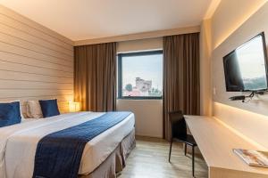 una camera d'albergo con letto, scrivania e finestra di Hotel Contemporâneo - Royal Palm Hotels & Resorts a Campinas
