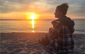 a woman sitting on the beach watching the sunset at Lovely Apartment In Bobolin With Kitchen in Bobolin