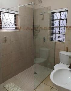 uma casa de banho com uma cabina de duche em vidro e um WC. em Devine Stay- Pmb em Pietermaritzburg