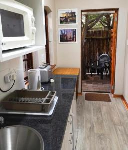 eine Küche mit einer Theke mit einer Spüle und einer Mikrowelle in der Unterkunft Devine Stay- Pmb in Pietermaritzburg