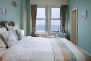 a bedroom with a large bed with a large window at The Beach Club in Penzance