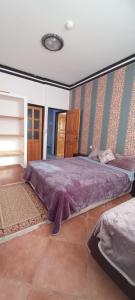 TamriにあるLa bananeraieのベッドルーム1室(紫のシーツが敷かれた大型ベッド1台付)