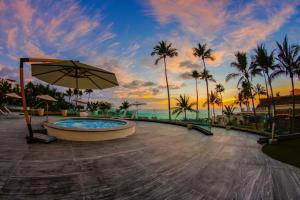 a hot tub with an umbrella next to the ocean at Sunset Plaza Beach Resort Puerto Vallarta All Inclusive in Puerto Vallarta
