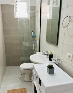 W łazience znajduje się umywalka, toaleta i lustro. w obiekcie TERRACE VIEW APARTMENTS w Sarandzie