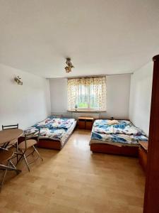 a bedroom with two beds and a table and a window at Pensjonat Sabina in Koszarawa