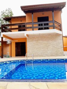 a villa with a swimming pool in front of a house at Casa de férias in Caraguatatuba