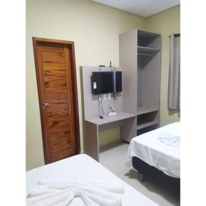 a bedroom with two beds and a tv on a wall at Pousada BarbacoaR in Parnaíba