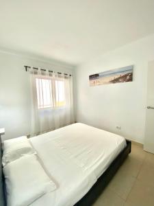 a white bedroom with a large bed and a window at APARTAMENTO EN LOS CRISTIANOS - FREE WIFI in Los Cristianos