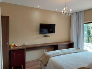 a bedroom with a bed and a tv on the wall at Costa del Mar Hotel Boutique in Miguel Pereira