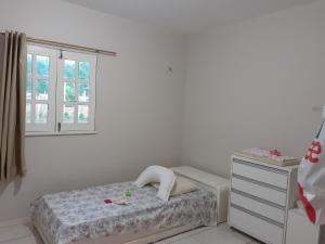 a bedroom with a bed and a dresser and a window at Sitio Vila Serrana in Ubajara