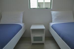 2 camas en una habitación con una mesa pequeña entre ellas en Oamaru Bay Tourist Park en Coromandel Town