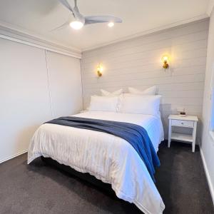 a bedroom with a white bed with a blue blanket at The Sandcastle House at Pelican Point in Carpenter Rocks