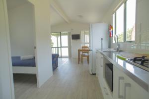 a kitchen with white cabinets and a counter top at Oamaru Bay Tourist Park in Coromandel Town