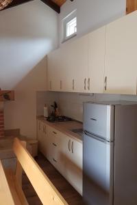  La cuisine est équipée de placards blancs et d'un réfrigérateur. dans l'établissement Secluded holiday house Postira, Brac - 17571, à Postira