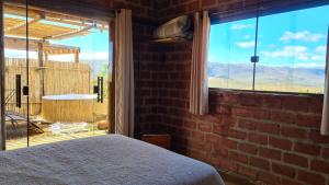 1 dormitorio con pared de ladrillo y ventana grande en Bangalô do Amor, en Serra do Cipo