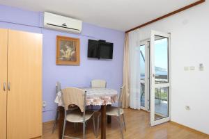 uma sala de jantar com uma mesa e uma televisão numa parede roxa em Apartments by the sea Duce, Omis - 17661 em Duće