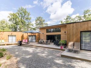 a house with a patio with chairs and an umbrella at Grande maison en bois avec parc, terrasse, jeux et équipements modernes entre Nantes et Pornic - FR-1-306-1051 in Port-Saint-Père
