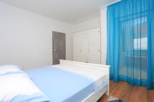 Schlafzimmer mit einem weißen Bett und blauen Vorhängen in der Unterkunft Apartment Solin 17669a in Solin