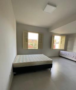 a bedroom with a bed in a room with two windows at Casa Ouro no centro de Diamantina in Diamantina