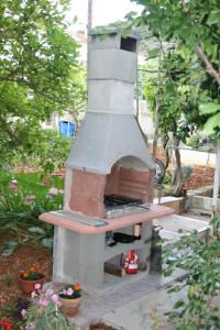 a outdoor pizza oven sitting in a garden at Apartments by the sea Vinisce, Trogir - 17590 in Vinišće